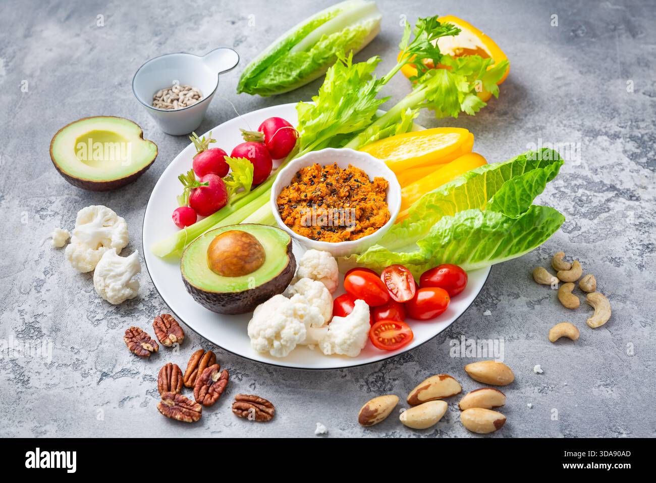 Verschiedene Snacks mit rohem Gemüse mit Karotten-Hummus und Nüssen Stockfoto