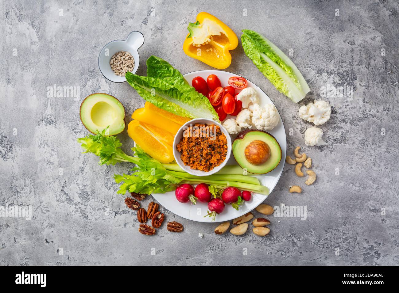 Verschiedene Snacks mit rohem Gemüse mit Karotten-Hummus und Nüssen Stockfoto