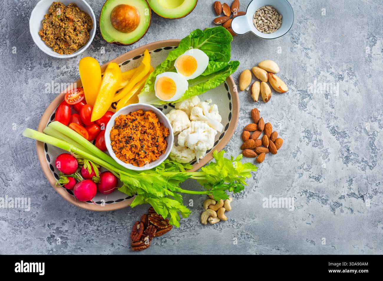 Verschiedene Snacks mit rohem Gemüse mit Karotten-Hummus und Nüssen Stockfoto