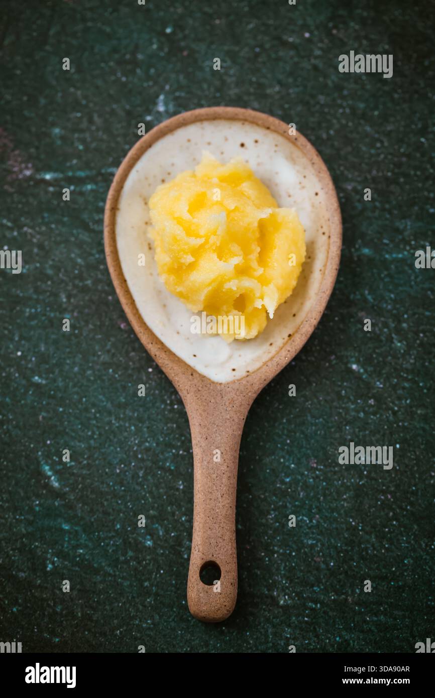 Laktosefreies Ghee, in kleinem Löffel auf dunklem Hintergrund, gesundes Kochen Stockfoto