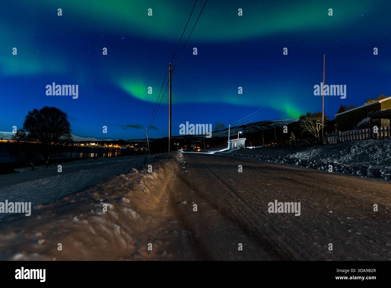 Leuchtend grüne Nordlichter leuchten über Tromsø, Norwegen, und werfen fließende aurorafuhren über den arktischen Nachthimmel Stockfoto