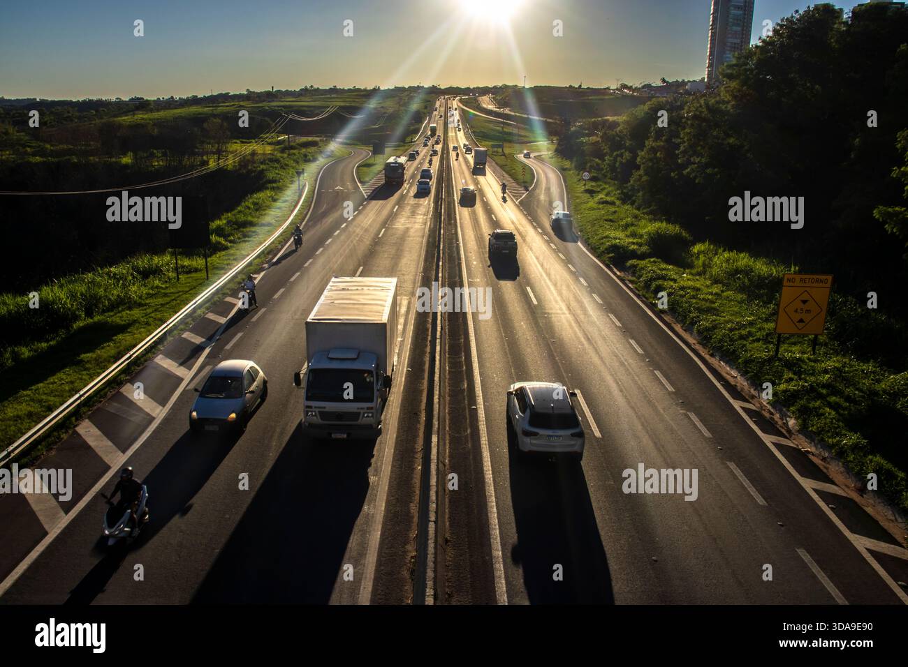 Marilia, SP, Brasilien, 19. November 2025. Autobahn SP-294 in Marilia, bei Sonnenuntergang. Der intensive Verkehr von Autos und LKWs fließt durch die grüne Landschaft Stockfoto