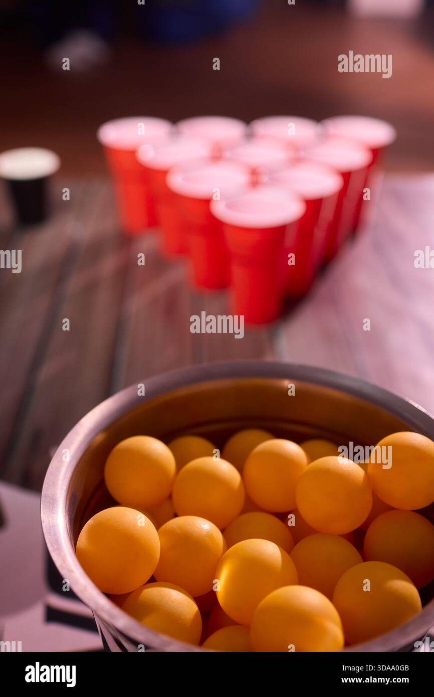 Partyspiel-Setup, verspielte Indoor-Szene mit Tischtennisbällen und Social-Media-Accessoires, warm beleuchtete Innenumgebung mit Bier-Pong-Essentials und Stockfoto