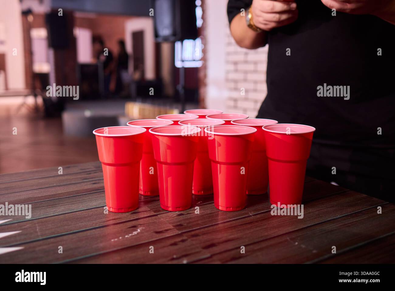 Partyspiel-Setup, verspielte Indoor-Szene mit Tischtennisbällen und Social-Media-Accessoires, warm beleuchtete Innenumgebung mit Bier-Pong-Essentials und Stockfoto