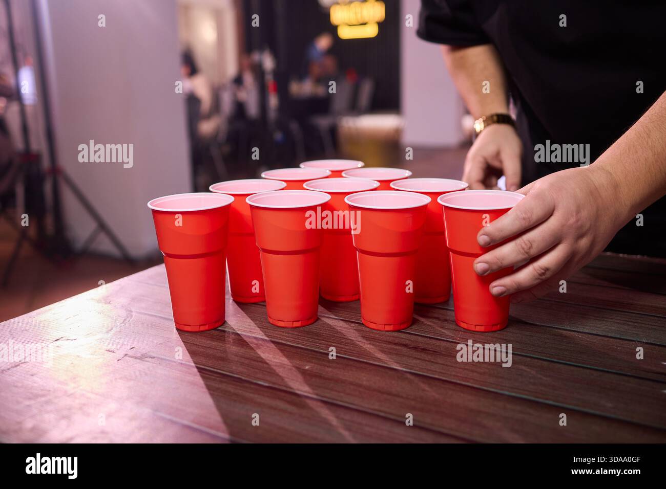 Partyspiel-Setup, verspielte Indoor-Szene mit Tischtennisbällen und Social-Media-Accessoires, warm beleuchtete Innenumgebung mit Bier-Pong-Essentials und Stockfoto