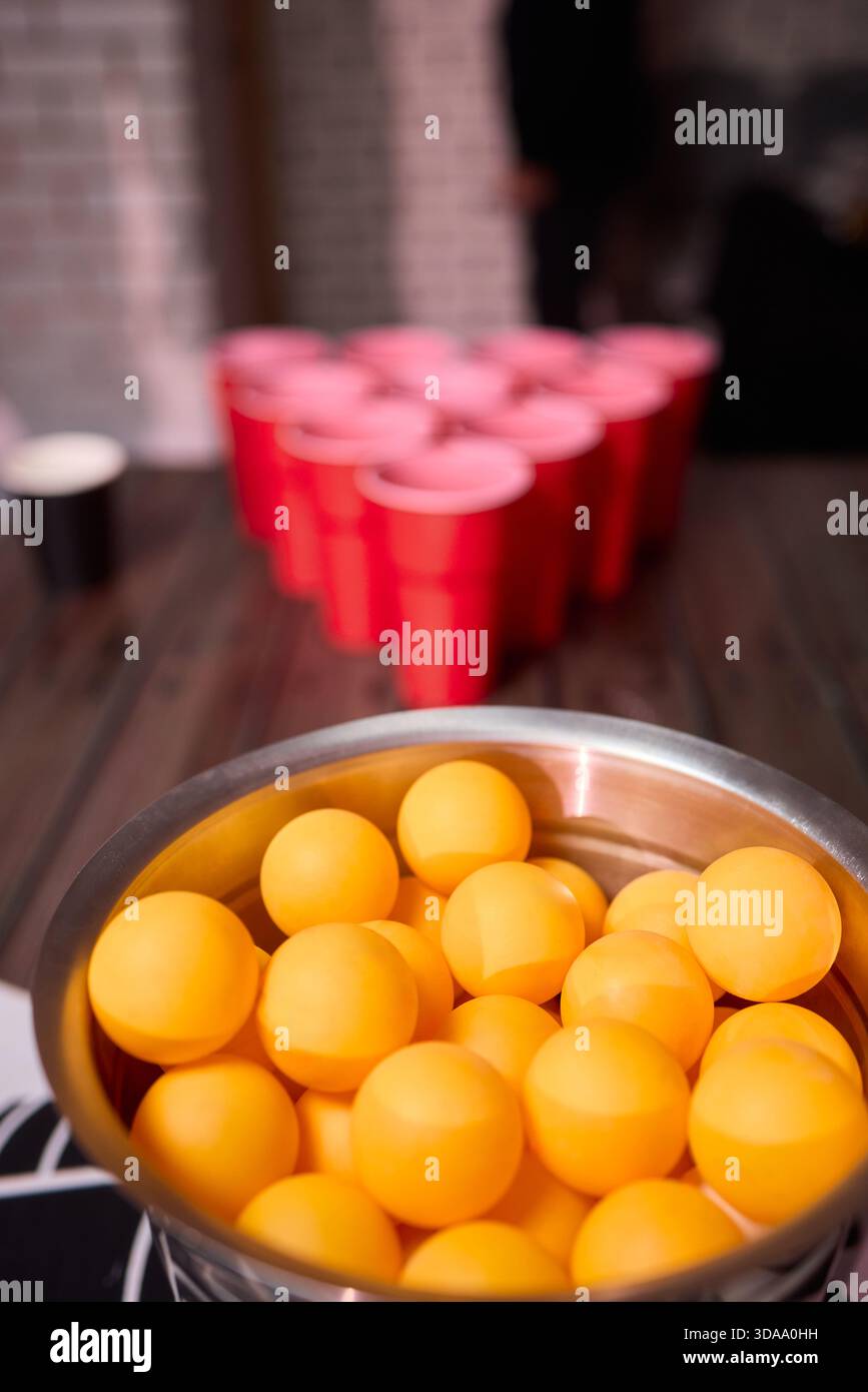 Partyspiel-Setup, verspielte Indoor-Szene mit Tischtennisbällen und Social-Media-Accessoires, warm beleuchtete Innenumgebung mit Bier-Pong-Essentials und Stockfoto
