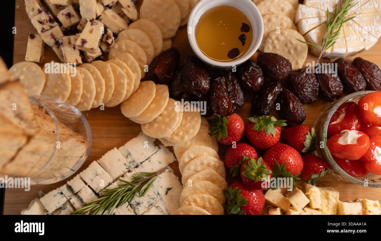 Wunderschöne Wurstplatte mit verschiedenen Käsesorten, frischem Obst, Datteln und mit Frischkäse gefüllten Paprika. Perfekt zum Teilen, für Partys oder für elegante Apps Stockfoto