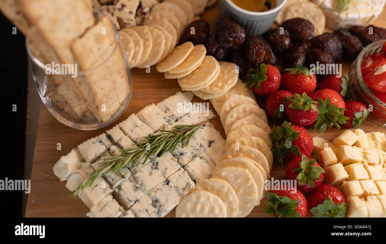Wunderschöne Wurstplatte mit verschiedenen Käsesorten, frischem Obst, Datteln und mit Frischkäse gefüllten Paprika. Perfekt zum Teilen, für Partys oder für elegante Apps Stockfoto