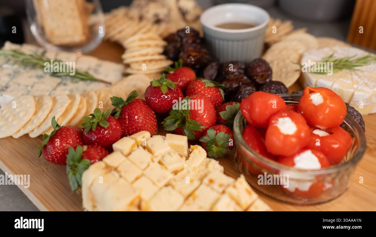 Wunderschöne Wurstplatte mit verschiedenen Käsesorten, frischem Obst, Datteln und mit Frischkäse gefüllten Paprika. Perfekt zum Teilen, für Partys oder für elegante Apps Stockfoto