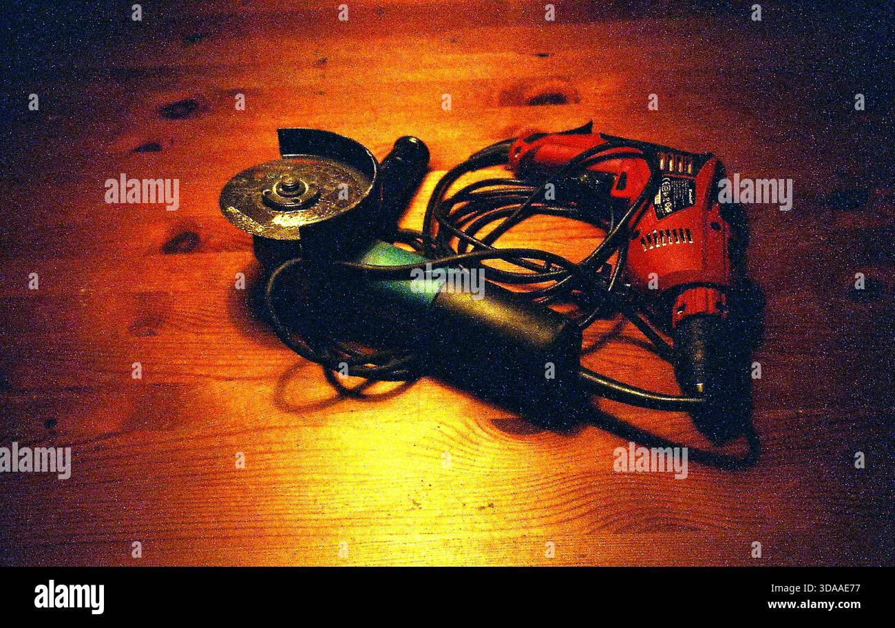 Analoge Aufnahme eines Schleifers und einer Basilika auf einem Holztisch, beleuchtet von Kronleuchter Licht, einfangen starken Kontrast und rustikale Texturen. Stockfoto