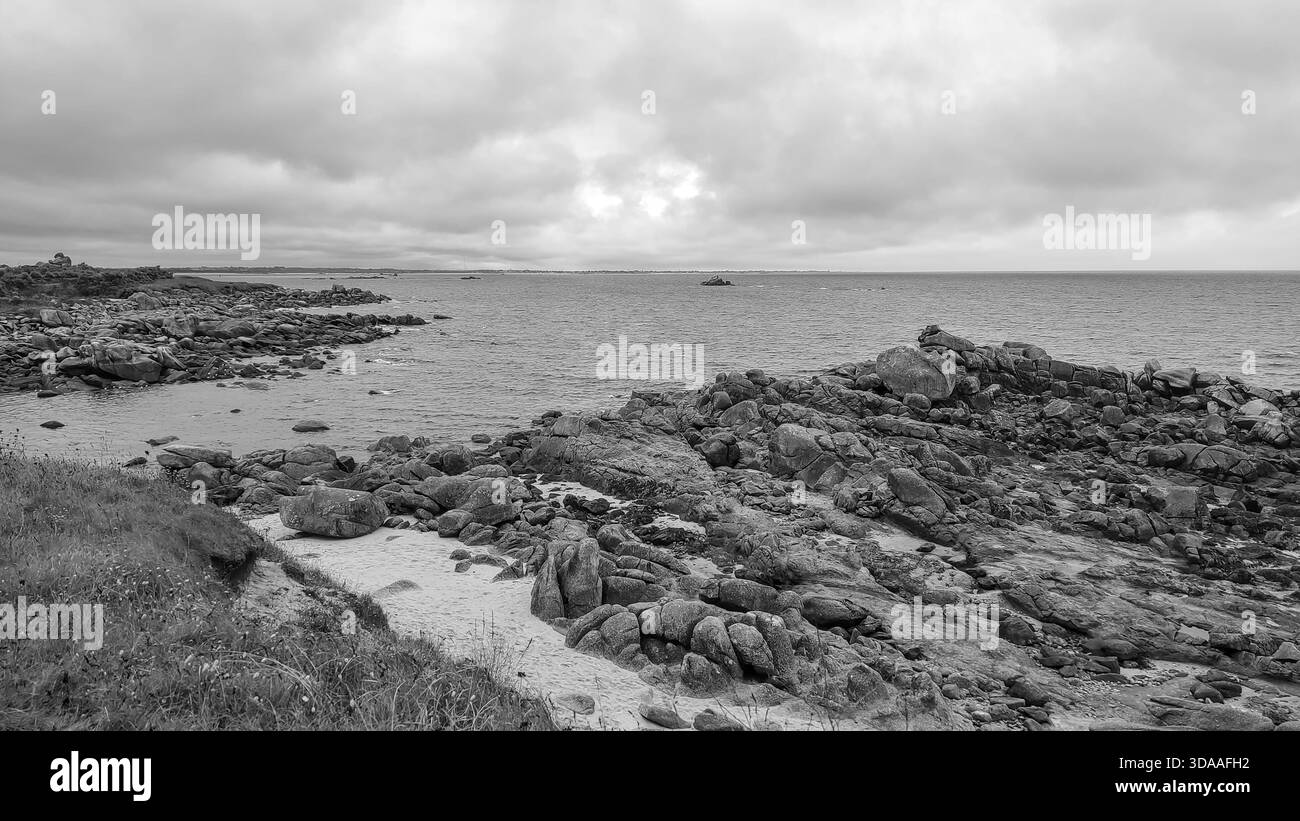 Felsige Steinküste mit Blick auf einen bewölkten Horizont, die eine dramatische und ruhige Atmosphäre schafft Stockfoto