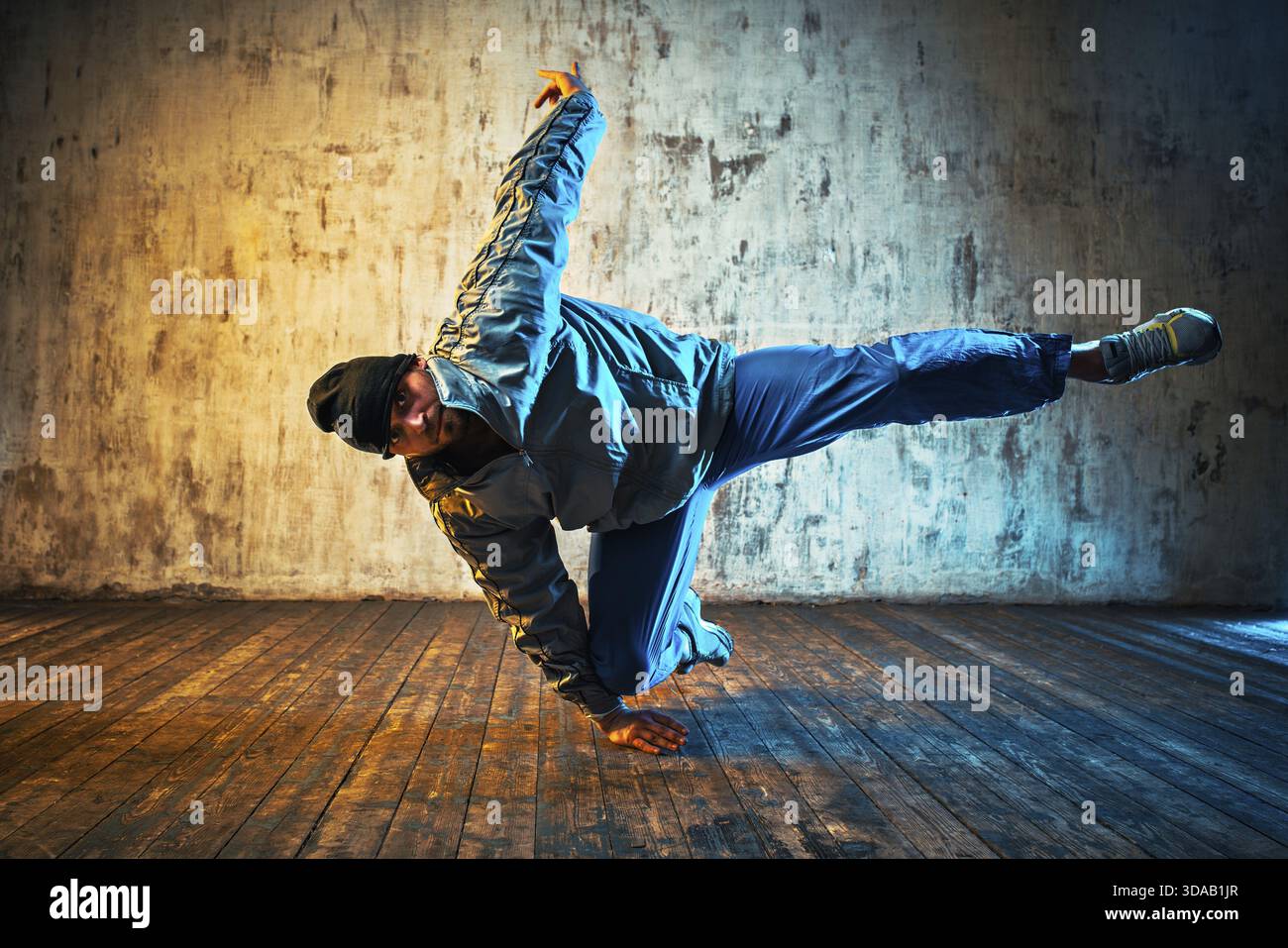 Junger Mann, der auf Wandhintergrund tanzt. Lebendige Farbeffekte Stockfoto