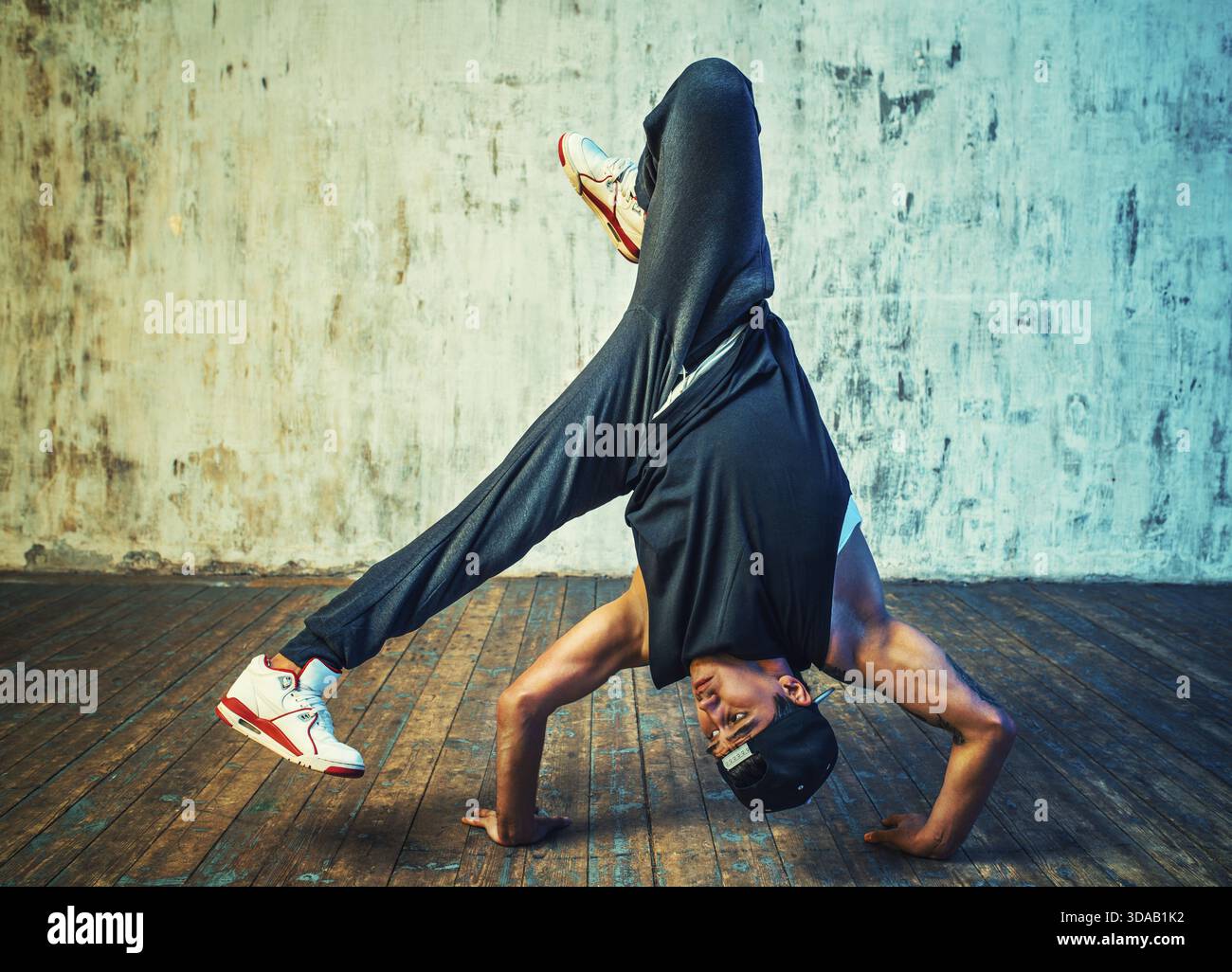 Junger Mann, der auf Wandhintergrund tanzt. Tätowierung am Körper Stockfoto