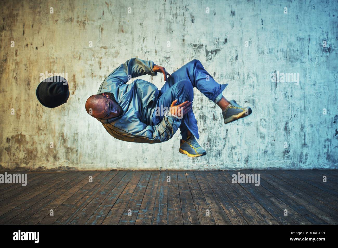 Junger Mann, der auf Wandhintergrund tanzt. In der Luft drehen Stockfoto