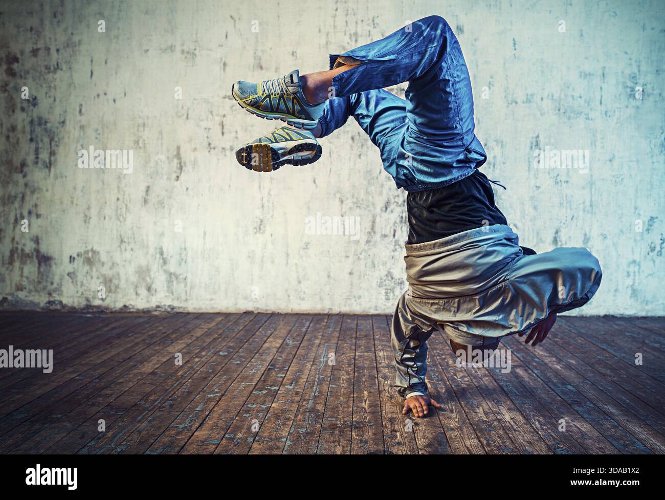 Junger Mann, der auf Wandhintergrund tanzt. Lebendige Farbeffekte Stockfoto