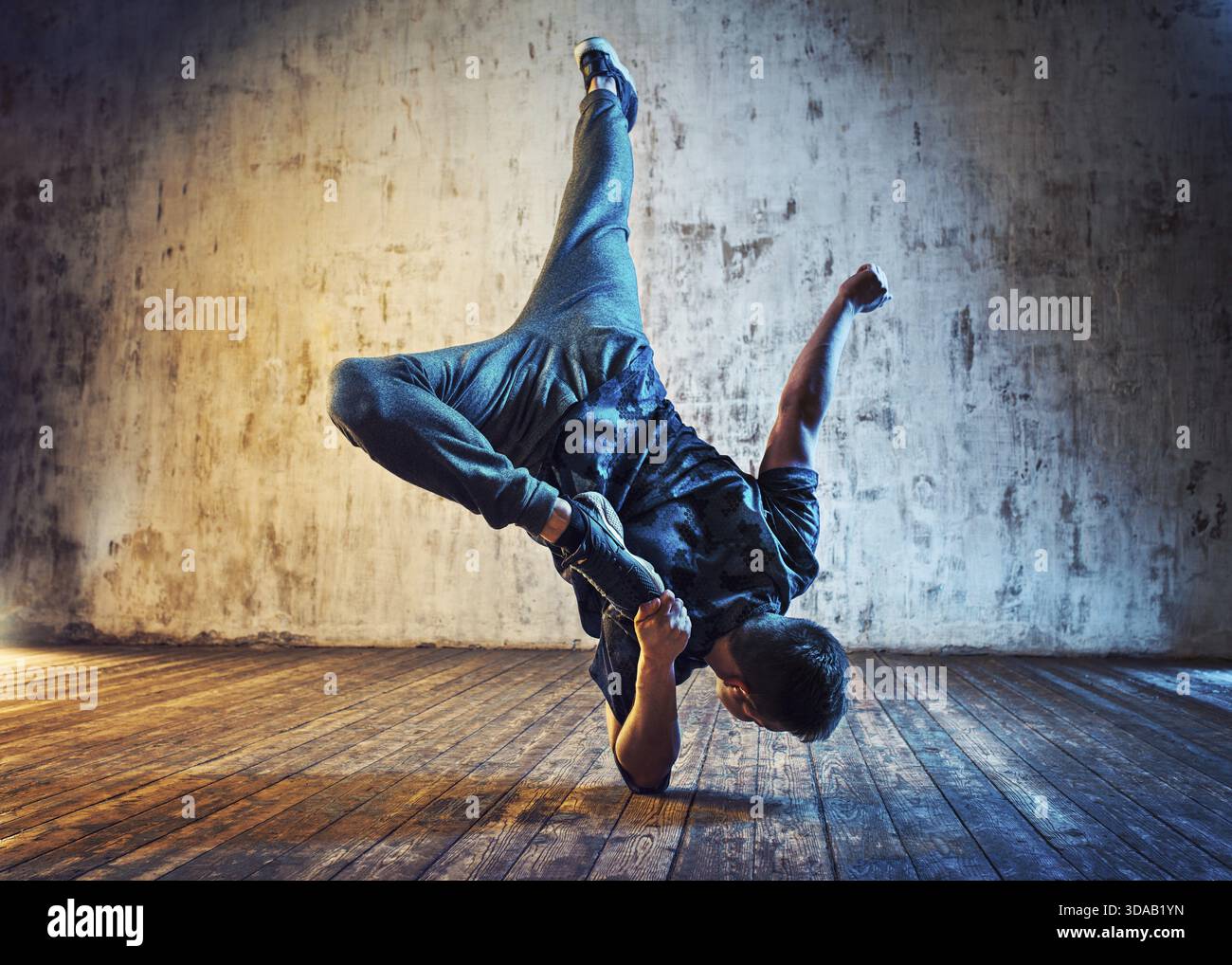 Junger Mann, der auf Wandhintergrund tanzt. Blaue und rote Lichteffekte Stockfoto