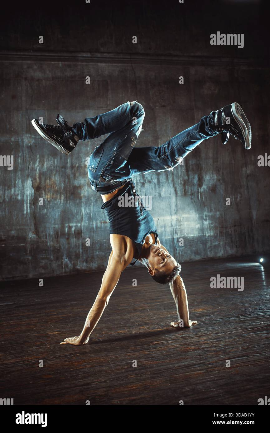 Junger Mann, der auf alter Wand tanzt. Farben im Vintage-Filmstil Stockfoto