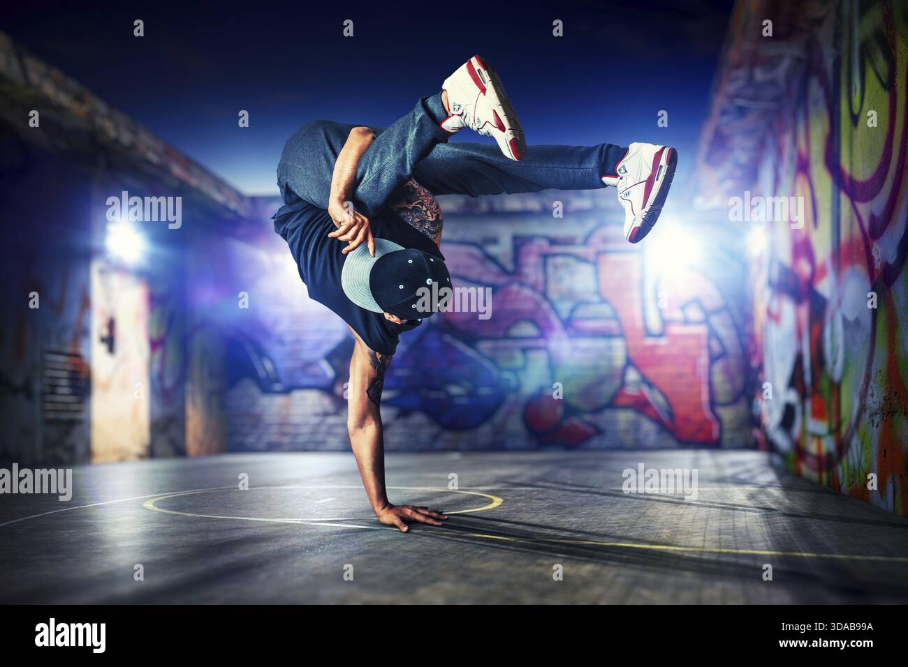 Junger Mann Breakdance in der Nacht auf städtischen gestrichene Wände Hintergrund Stockfoto