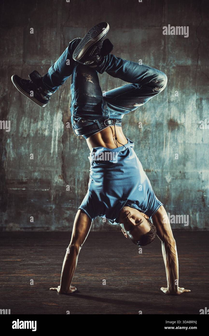 Junger Mann, der auf alter Wand tanzt. Farben im Vintage-Filmstil Stockfoto