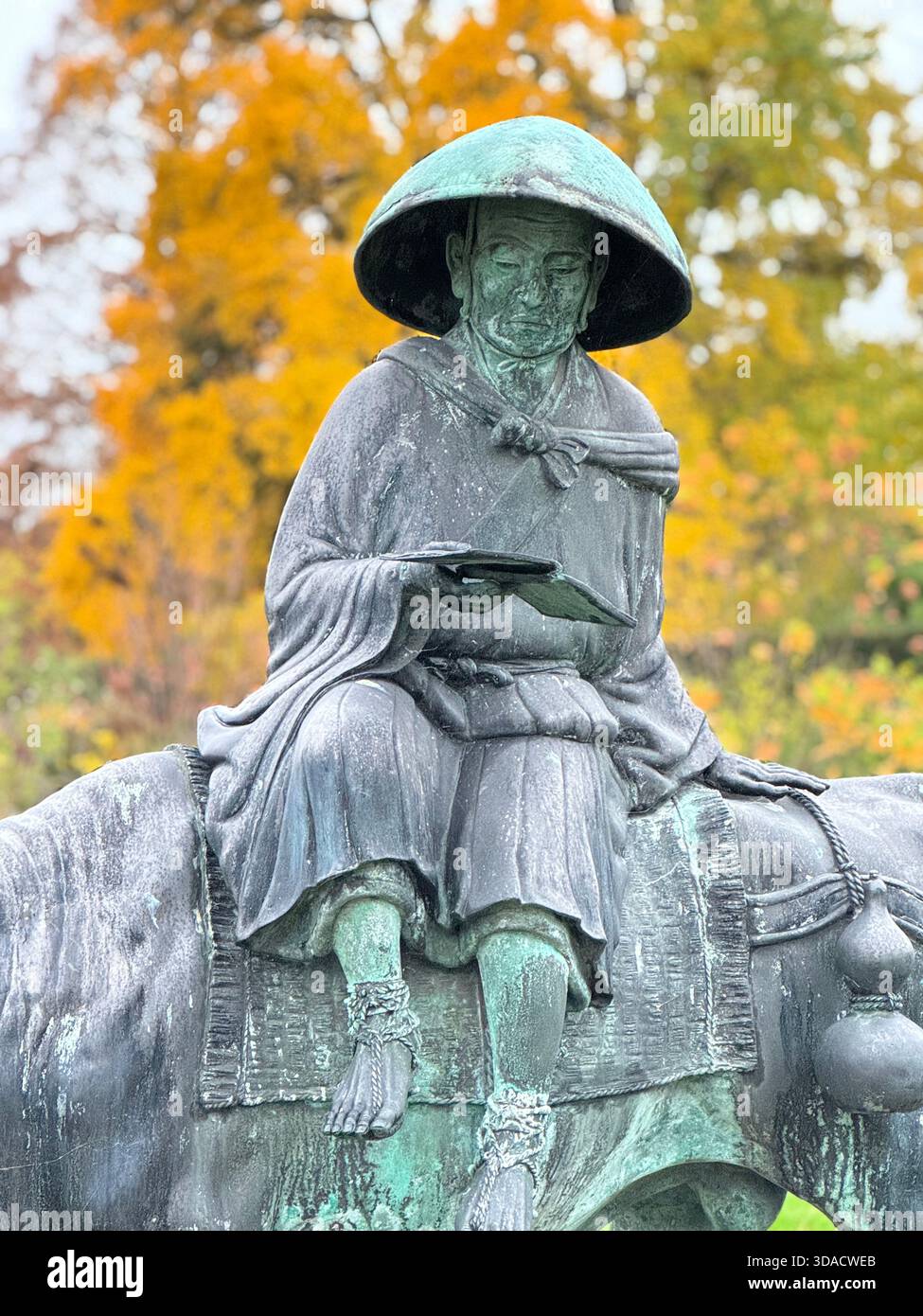 Bronzestatue in Dyffryn Gardens eines Mannes, der auf der Rückseite eines Wasserbüffels liest, Vale of Glamorgan, Südwales. - Smartphone-aufgenommenes Stockfoto