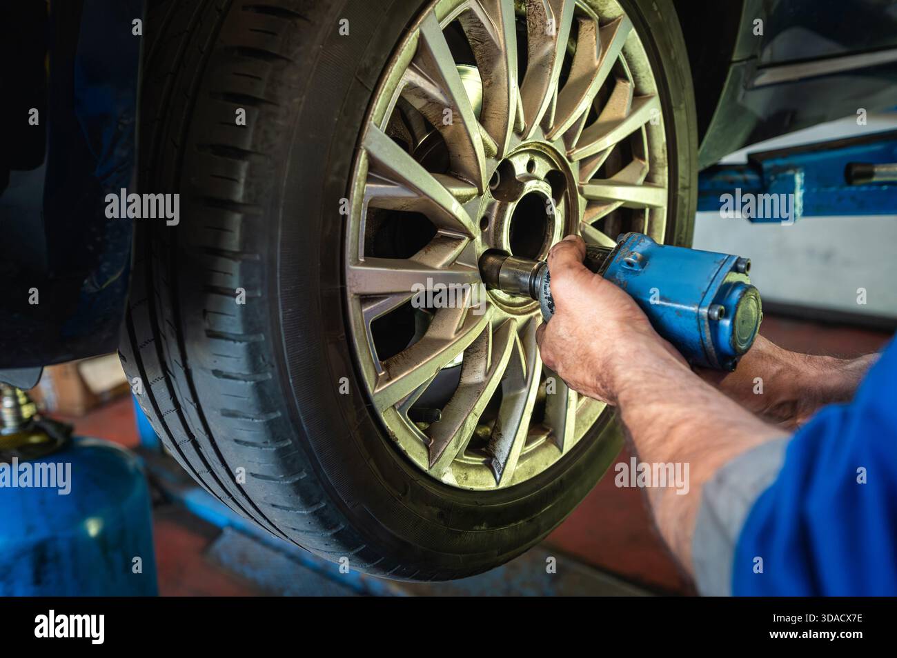 Techniker mit Schlagschrauber zum Entfernen der Radmuttern vom Autorad in einer Garage Stockfoto