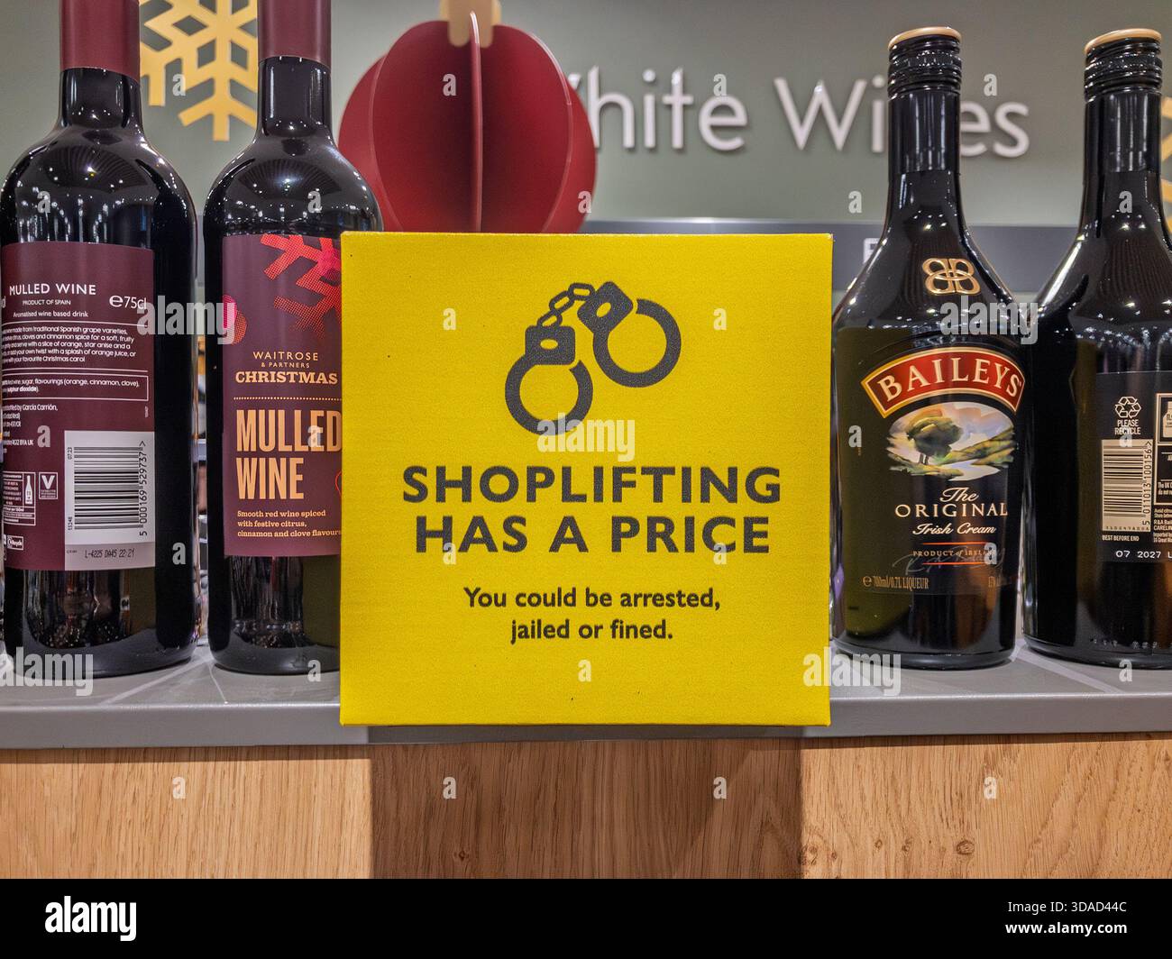 Warnschild mit Handschellen im Weinbereich eines Waitrose-Supermarktes, Warnung vor Verhaftung, Geldstrafen oder Gefängnis in Großbritannien Stockfoto