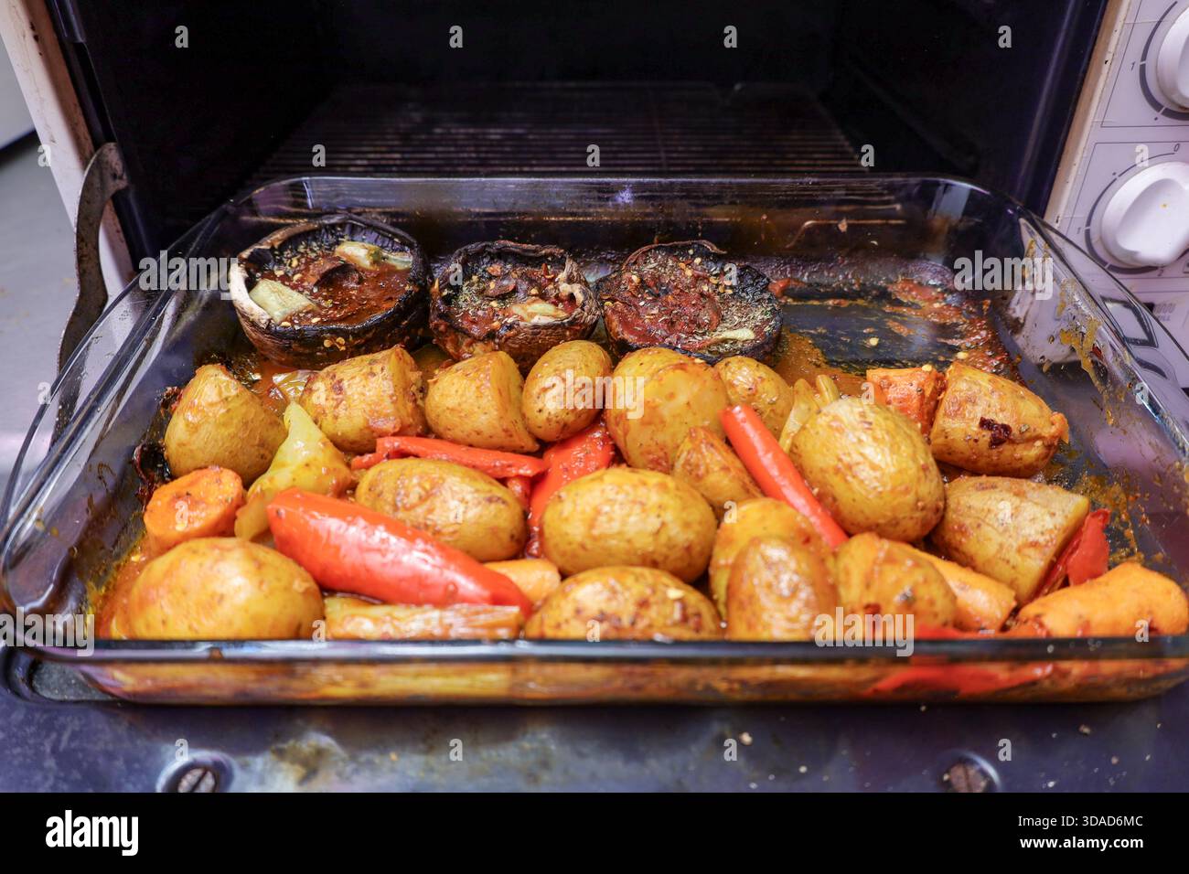 Rustikales hausgemachtes Gericht mit gebratenen Babykartoffeln, Karotten, roten Paprika und gewürzten portobello-Pilzen Stockfoto