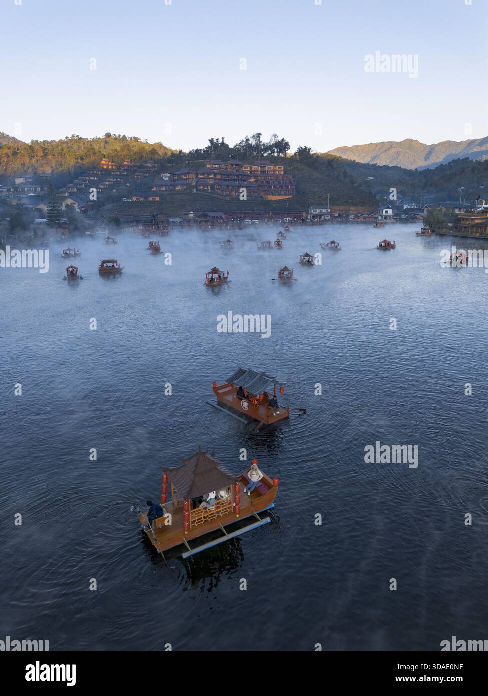 Ruhige Morgenlandschaft des traditionellen Dorfes in Thailand. Hölzerne Boot für Reisen und Tourismus schwimmt auf einem ruhigen See, umgeben von beschaulichen Nebelkreationen Stockfoto