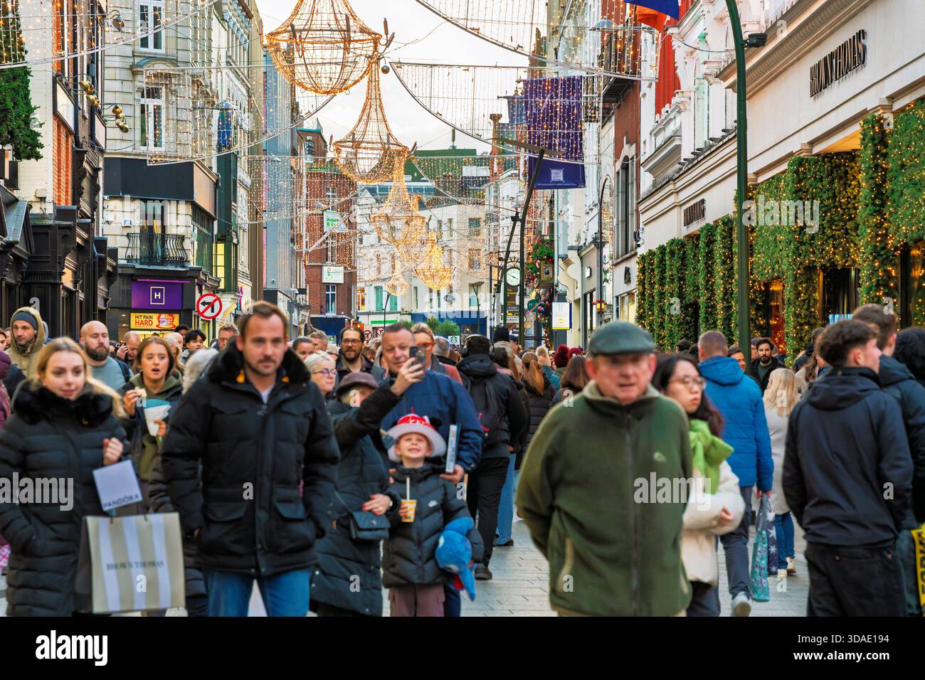 Lebhafte Grafton Street zu Weihnachten mit beleuchteten Kronleuchtern, Käufern und warmen Weihnachtslichtern in Dublin Irland Stockfoto