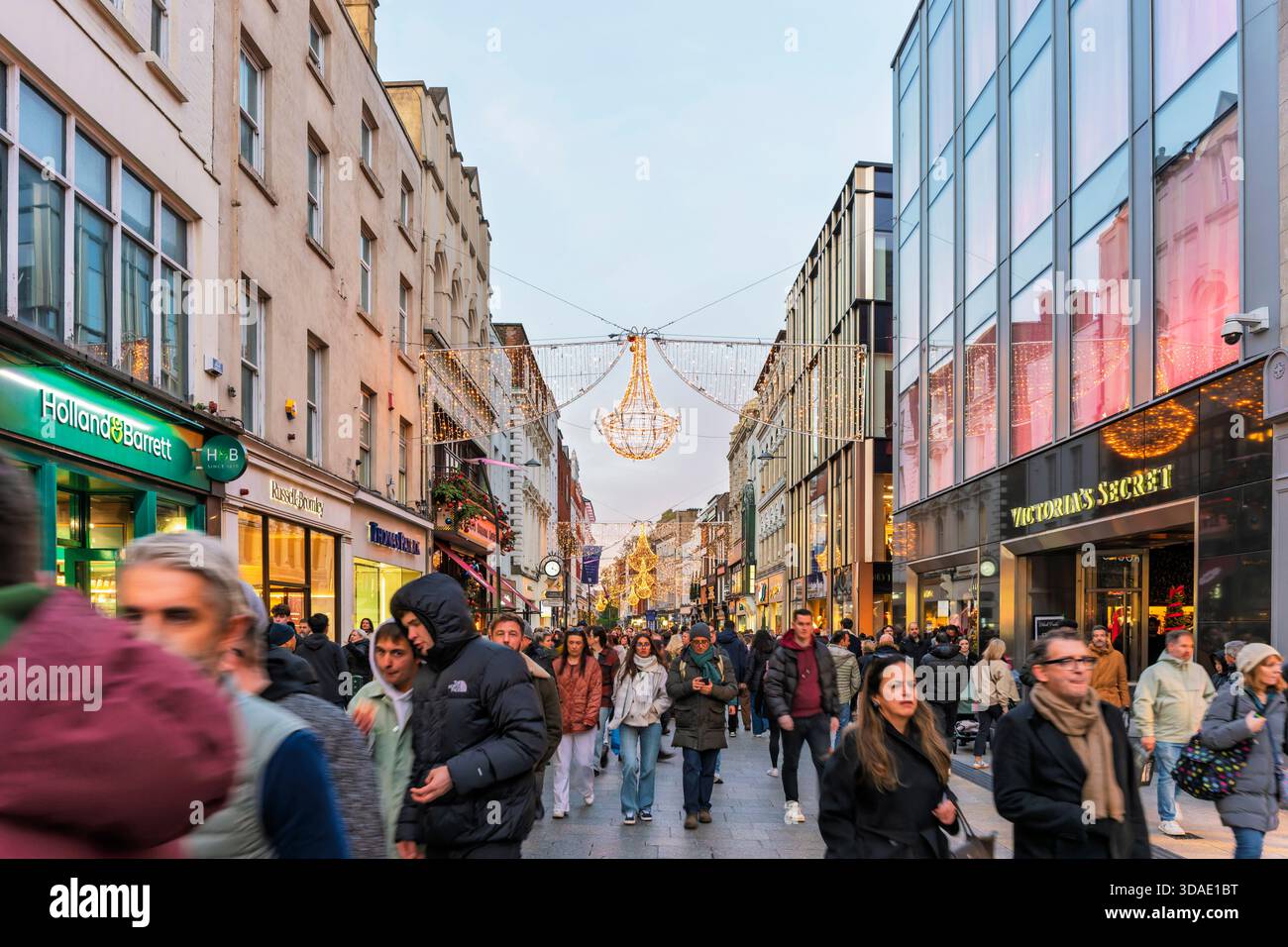 Lebhafte Grafton Street zu Weihnachten mit beleuchteten Kronleuchtern, Käufern und warmen Weihnachtslichtern in Dublin Irland Stockfoto