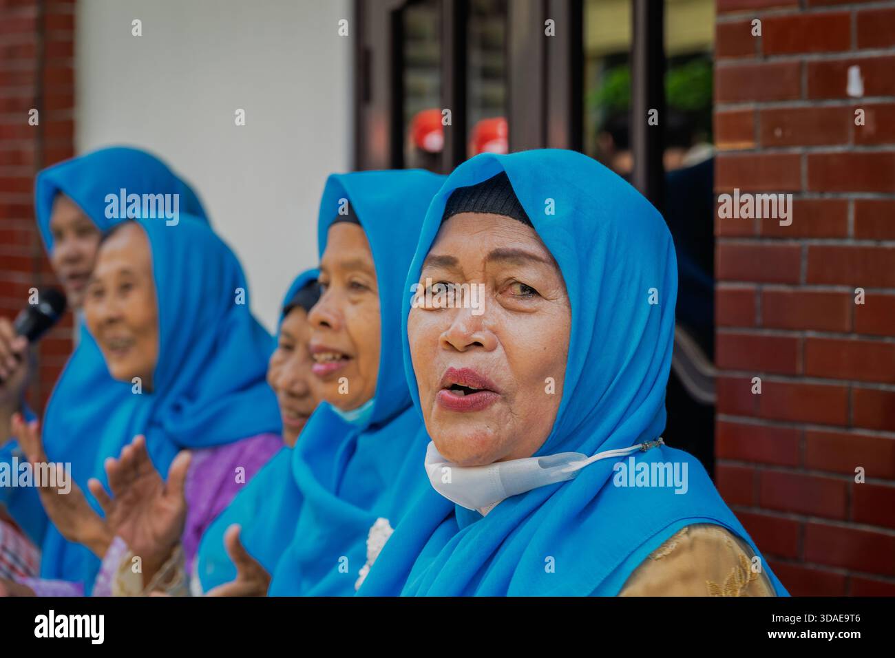 Surabaya, Indonesien--2. März 2023 versammeln sich verschiedene Frauen, tragen passende blaue Hijabs und lächeln. Stockfoto