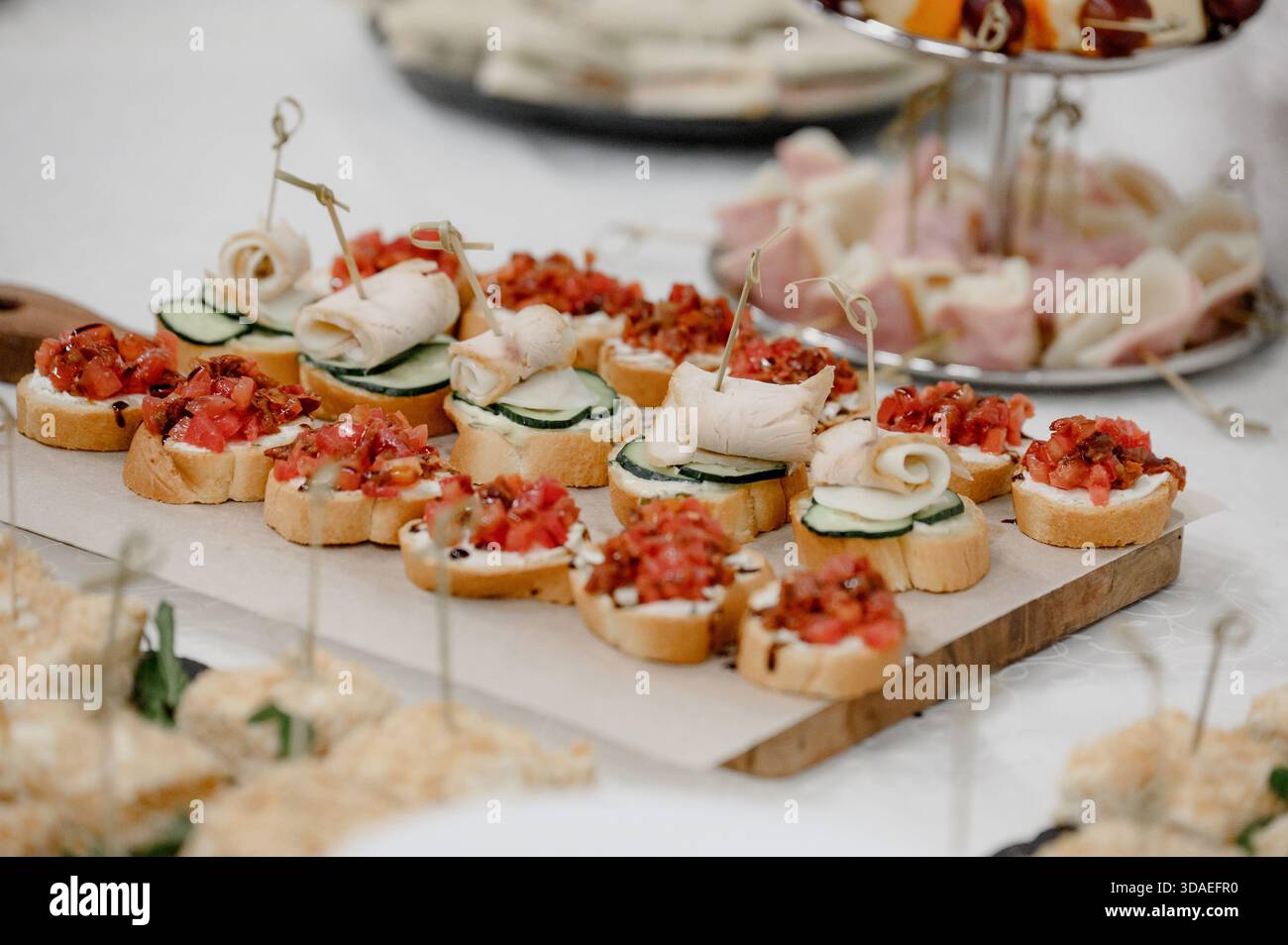 Bruschetta mit Tomaten und Kanapees mit Gurke und Wurstwaren, Nahaufnahme. Eine Auswahl an kalten Vorspeisen, Bruschetta und Mini-Sandwiches mit mir Stockfoto