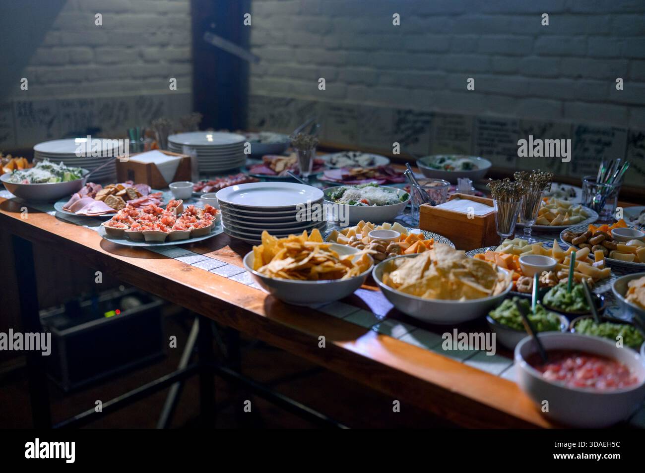 Ein Buffet mit Vorspeisen, Pommes Frites, Dips, Salaten und Aufschnitt. Ein festliches Abendessen mit Buffetspeisen, Vorspeisen und weißen Tellern für den Veranstaltungsgast Stockfoto