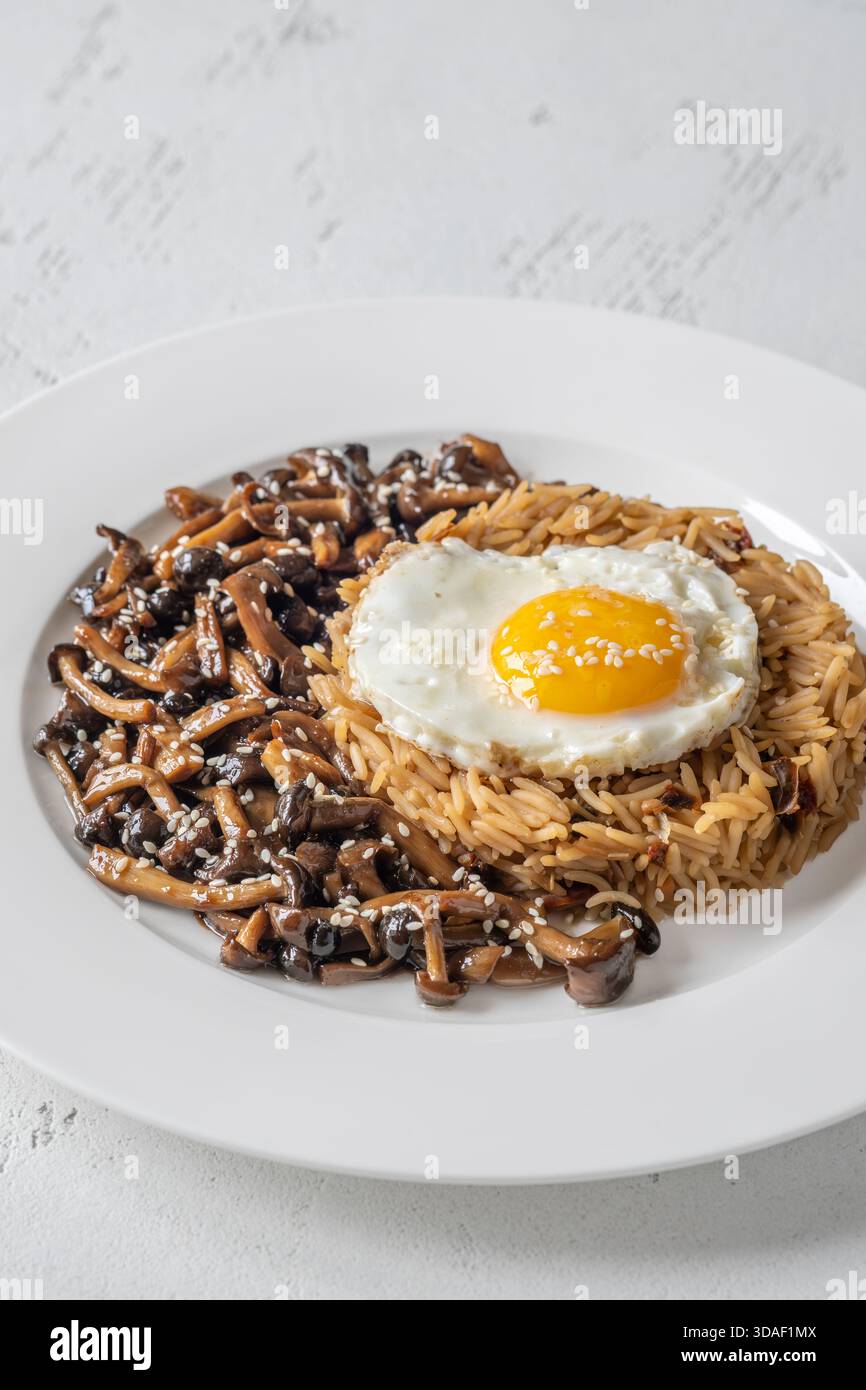 Das gemütliche Reisgericht besteht aus Butterpilzen, Sesamgarnitur und perfekt gekochtem Eigelb Stockfoto