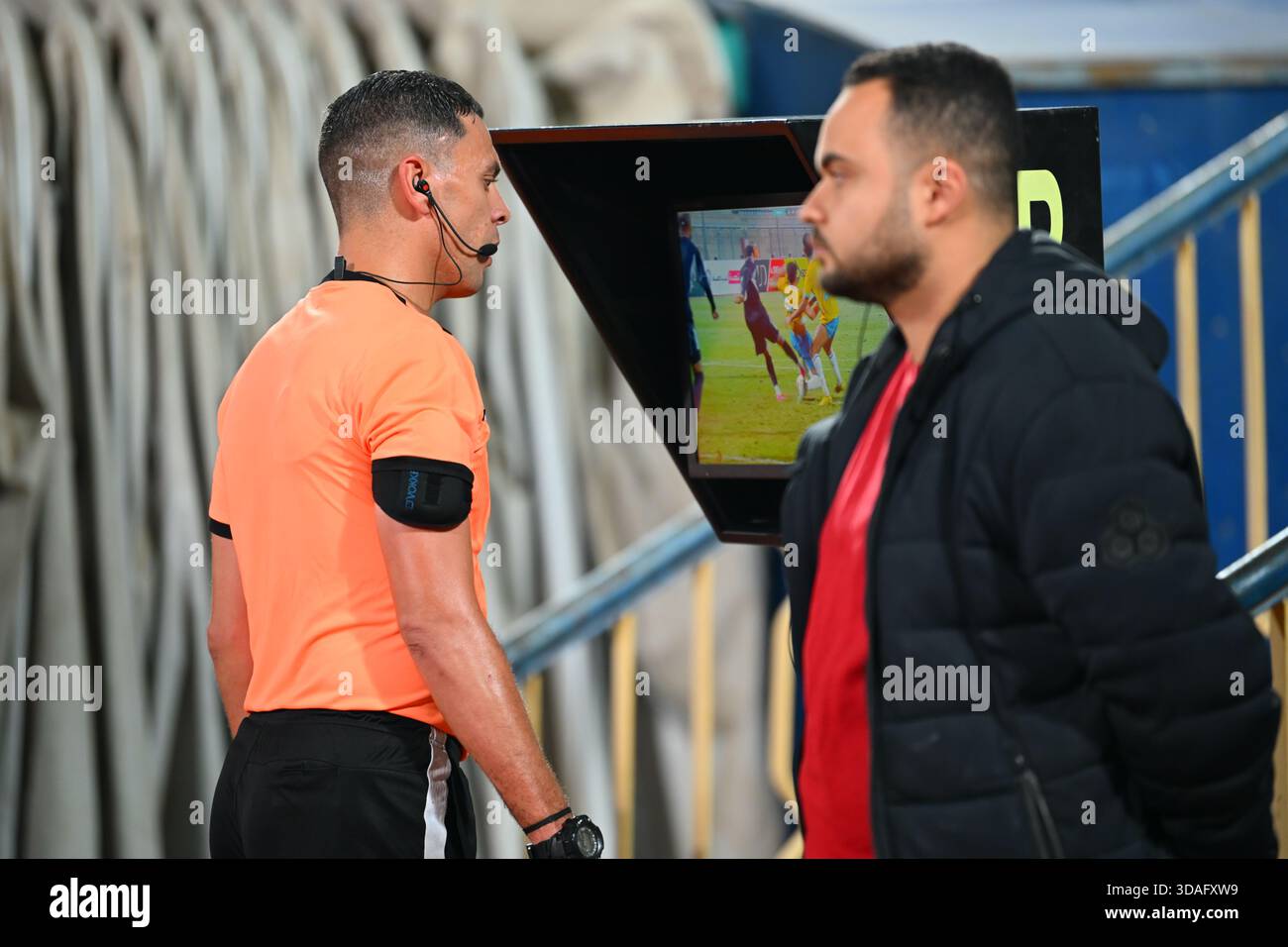 Ein Schiedsrichter überprüft einen Vorfall auf dem VAR-Monitor während eines Fußballspiels. Stockfoto