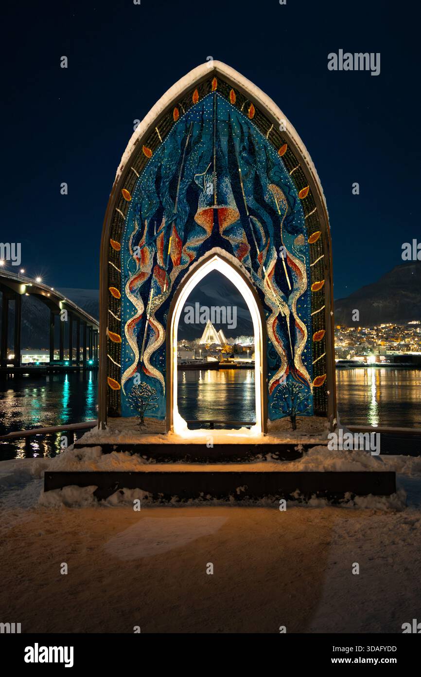 Nachtblick auf den Mosaikbogen in Tromsø, Norwegen, mit Blick auf modernes skandinavisches Design und beleuchtete städtische Architektur. Stockfoto