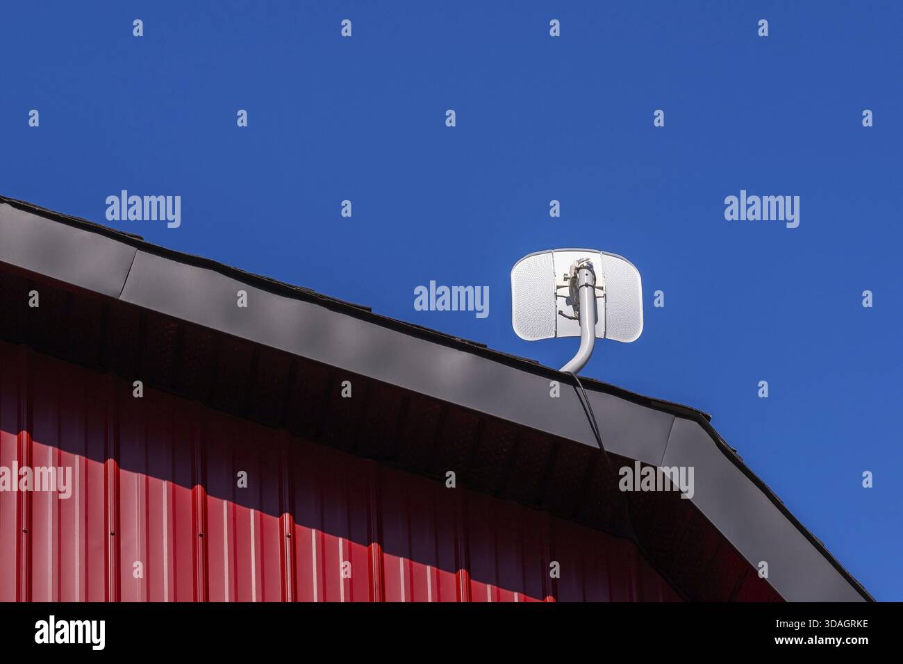 Weiße Satellitenantenne auf dem Giebeldach des Gebäudes mit rotem Blechverkleidungen und schwarzer Metallverkleidung, Quebec, Kanada Stockfoto