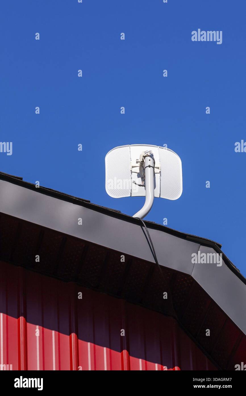 Weiße Satellitenantenne auf dem Giebeldach des Gebäudes mit rotem Blechverkleidungen und schwarzer Metallverkleidung, Quebec, Kanada Stockfoto