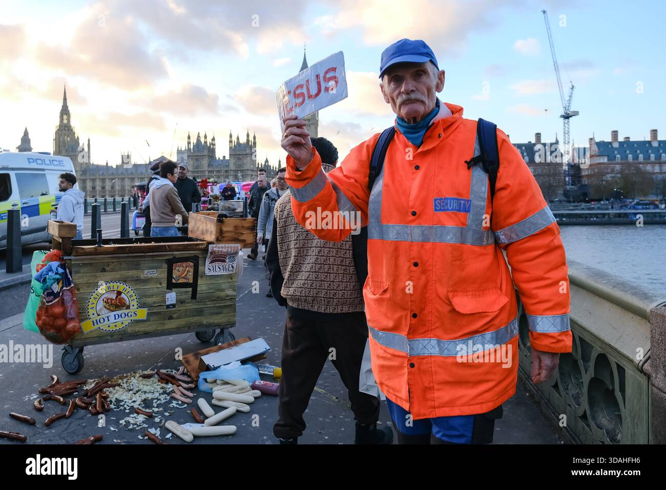 London, Großbritannien. Dezember 2025. Ein Mann mit einem kleinen Schild mit der Aufschrift "Jesus" geht die Westminster Bridge hoch und runter. Ein geschäftiger Tag in Westminster, da Weihnachten naht, mit immer mehr Besuchern und einer Vielzahl an saisonalen Aktivitäten in und um die Hauptstadt zieht Einheimische und Touristen gleichermaßen an. Quelle: Eleventh Photography/Alamy Live News Stockfoto