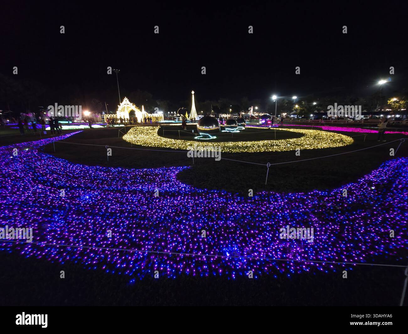 Magisches Nachtlicht-Festival im Park mit blendender violetter und gelber Beleuchtung. Diese Außendekoration sorgt für ein schönes und lebendiges Display für Stockfoto