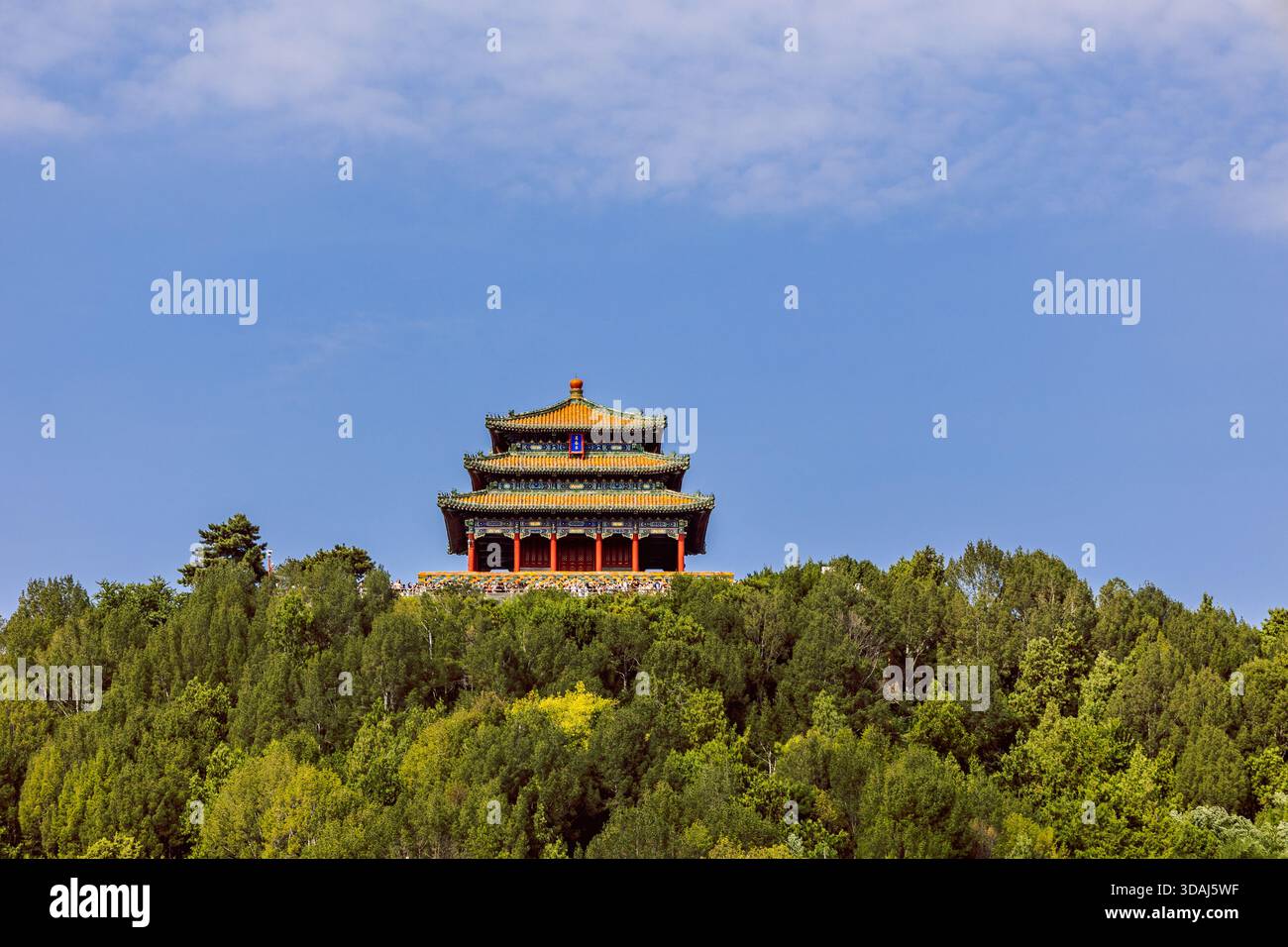 Der Pavillon auf einem Hügel mit mehrschichtigen Dachlinien erhebt sich über dichte grüne Bäume und bietet einen klaren Blick auf den traditionellen chinesischen Architekturstil Stockfoto