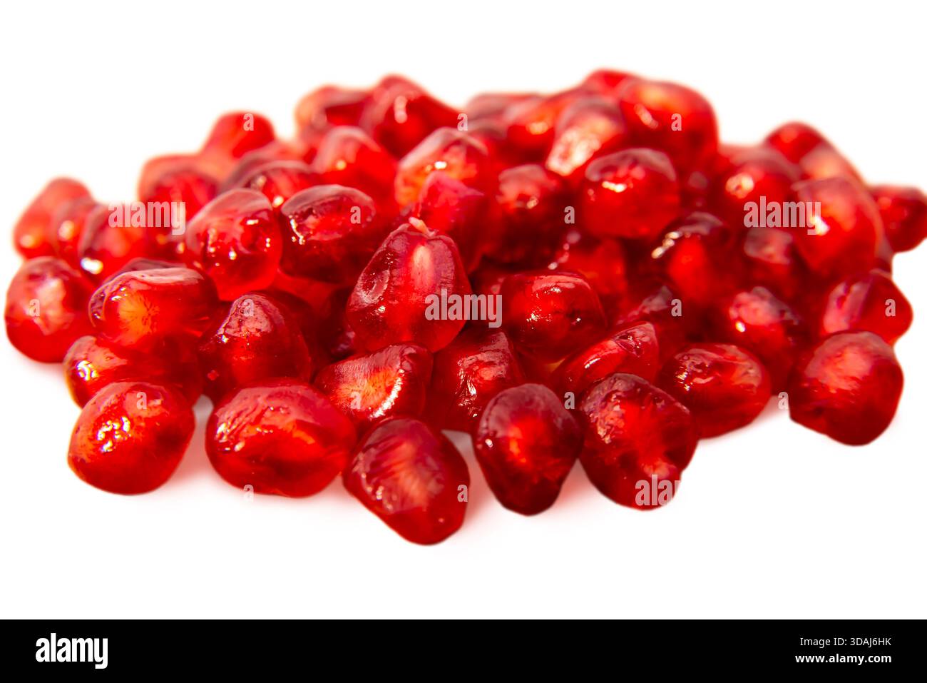 Frische Granatapfelkerne auf weißem Hintergrund, die ihre leuchtend rote Farbe und saftige Textur für gesunde Ernährung zeigen. Stockfoto