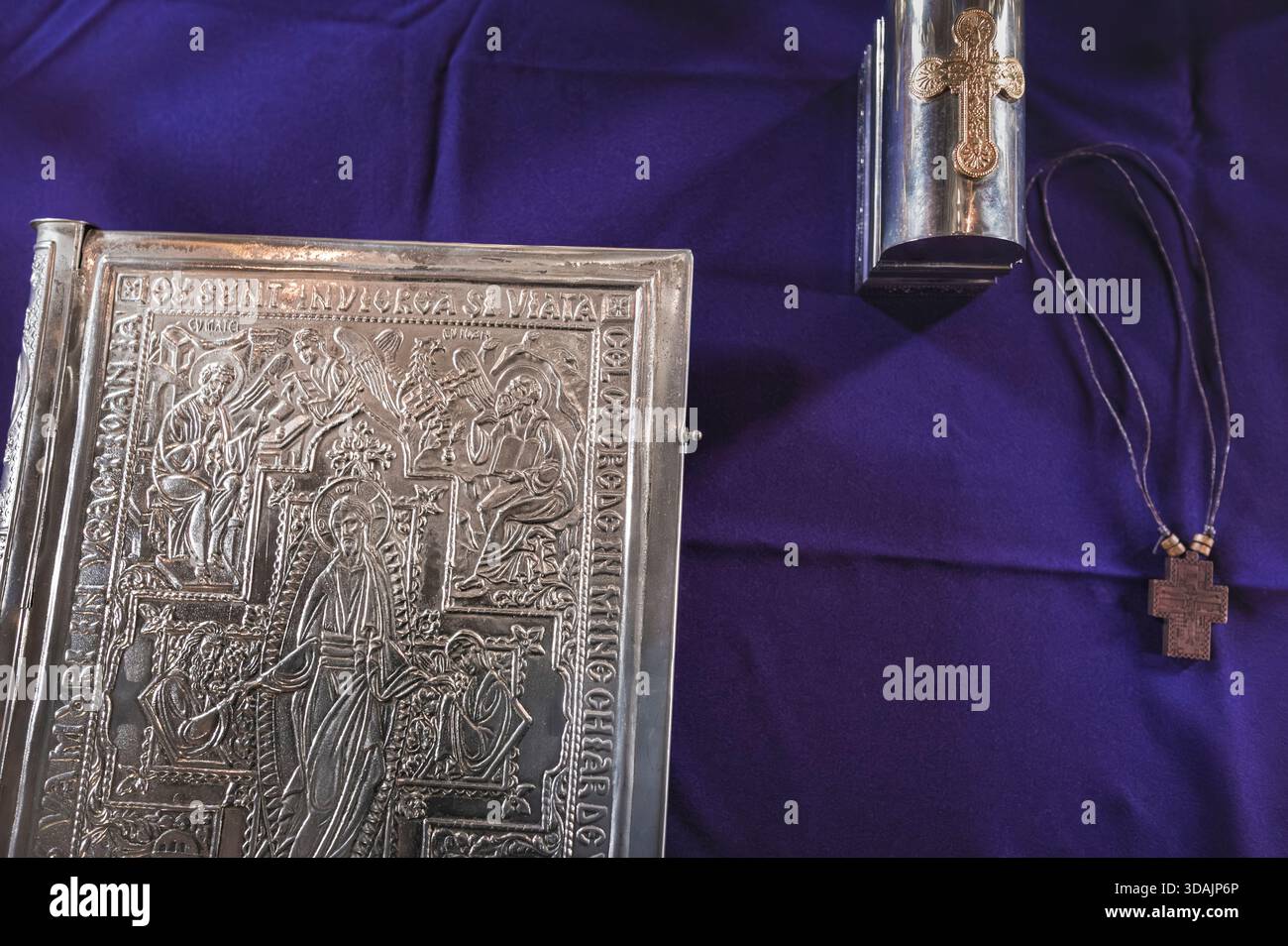 Petrosani, Rumänien 22. November 2025: Reich verziertes silbergebundenes Evangeliumsbuch hölzernes Kreuz Halskette Chrismenbox tiefviolett liturgisches Tuch Ritualobjekte Stockfoto