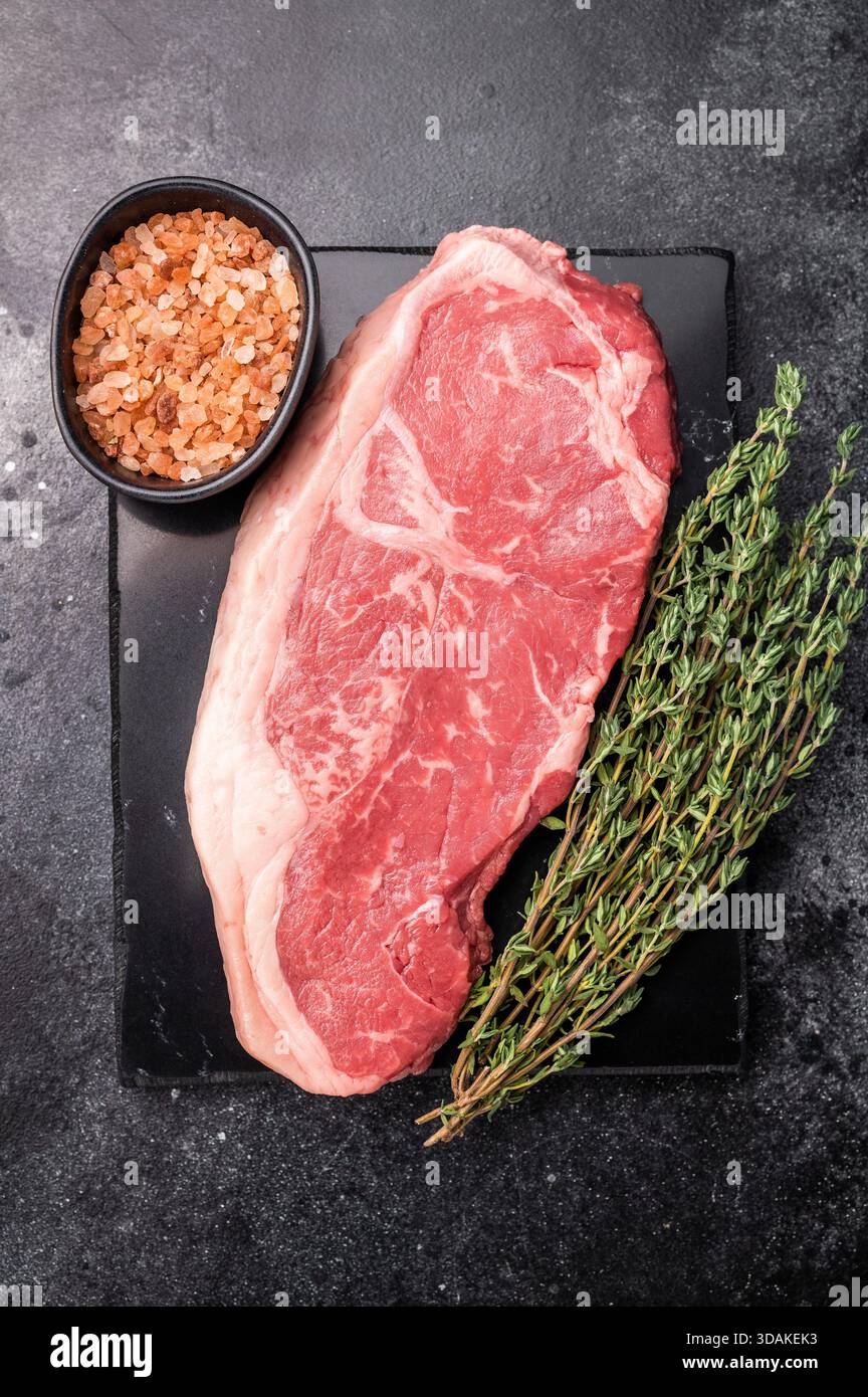 Rohe Rindersteaks mit Striploin, New York Strip Steak. Schwarzer Hintergrund. Draufsicht. Stockfoto