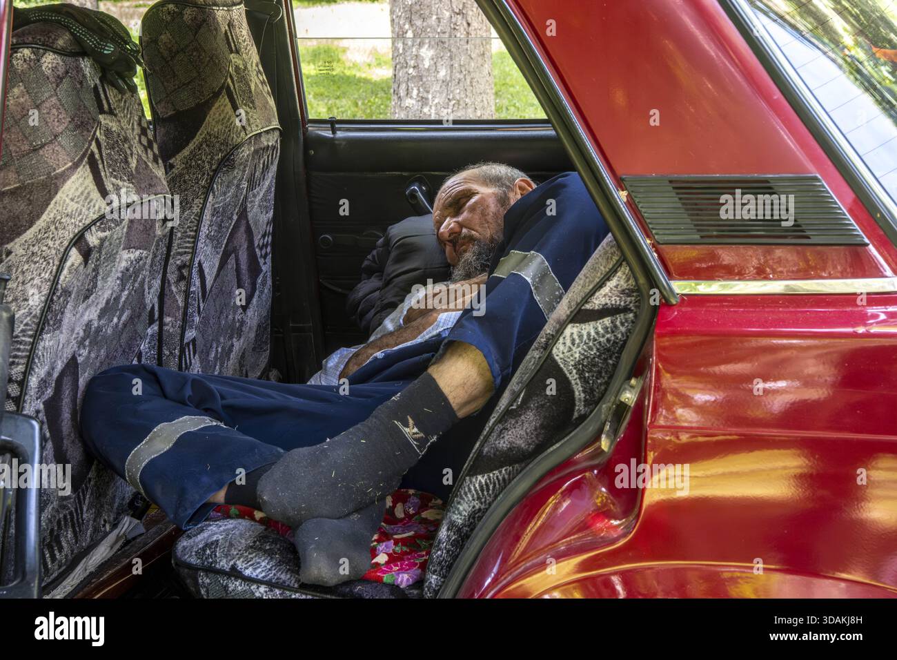 Mann, der in einem Auto in Samarkand, Usbekistan, schläft Stockfoto