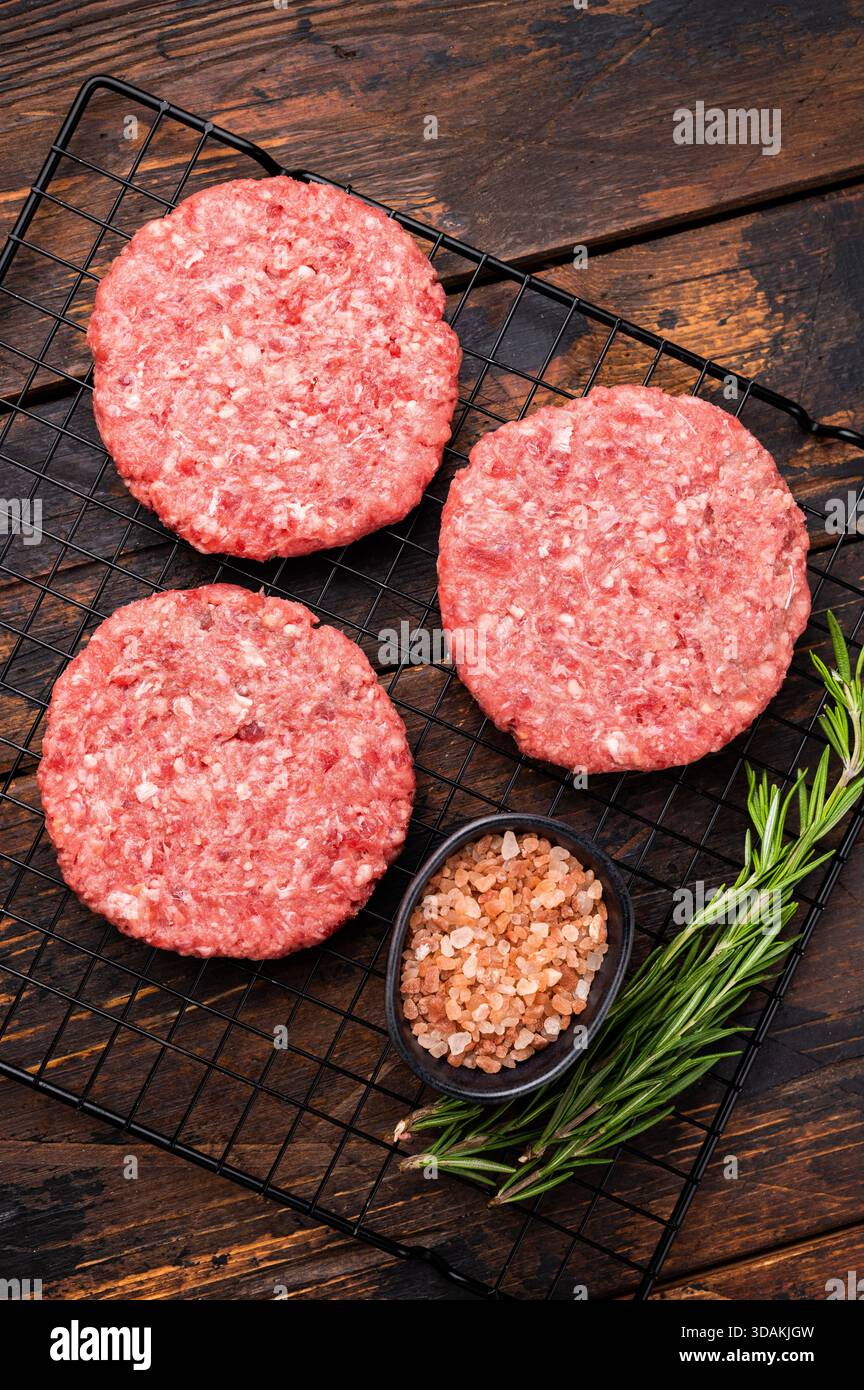 Rohe Fleischpasteten, Schnitzel, Hackfleisch für Burger. Hölzerner Hintergrund. Draufsicht Stockfoto