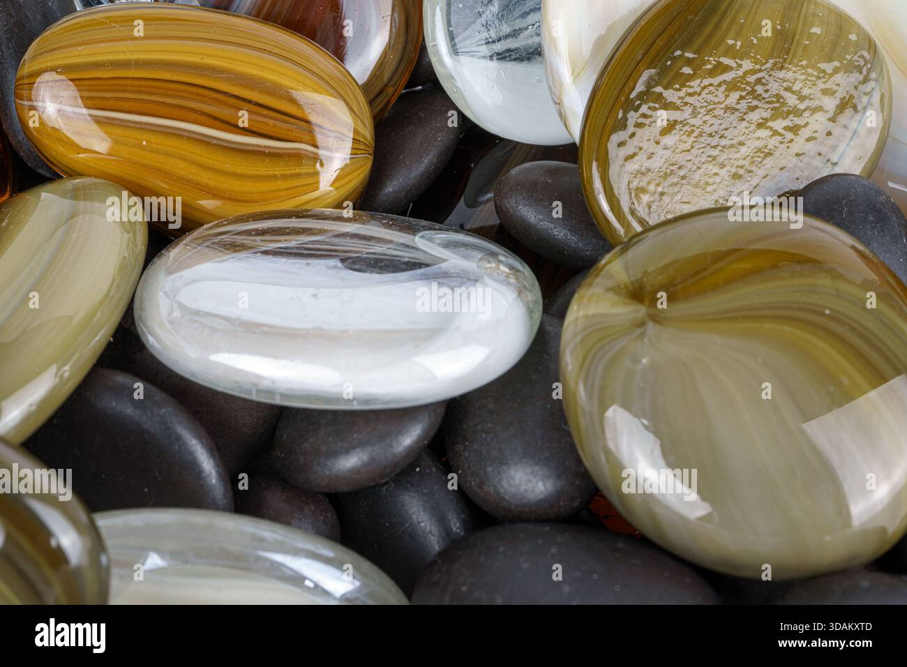 Polierte dekorative Glassteine auf glatten schwarzen Kieselsteinen. Stockfoto