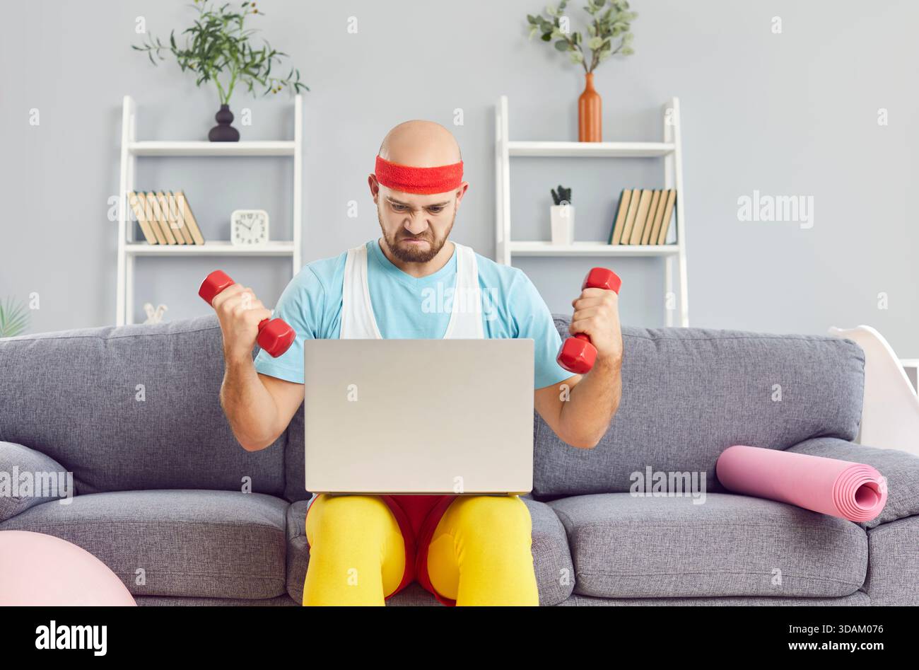 Ernster Mann In Lustiger Retro Sportswear Mit Laptop Für Heimtraining Stockfoto