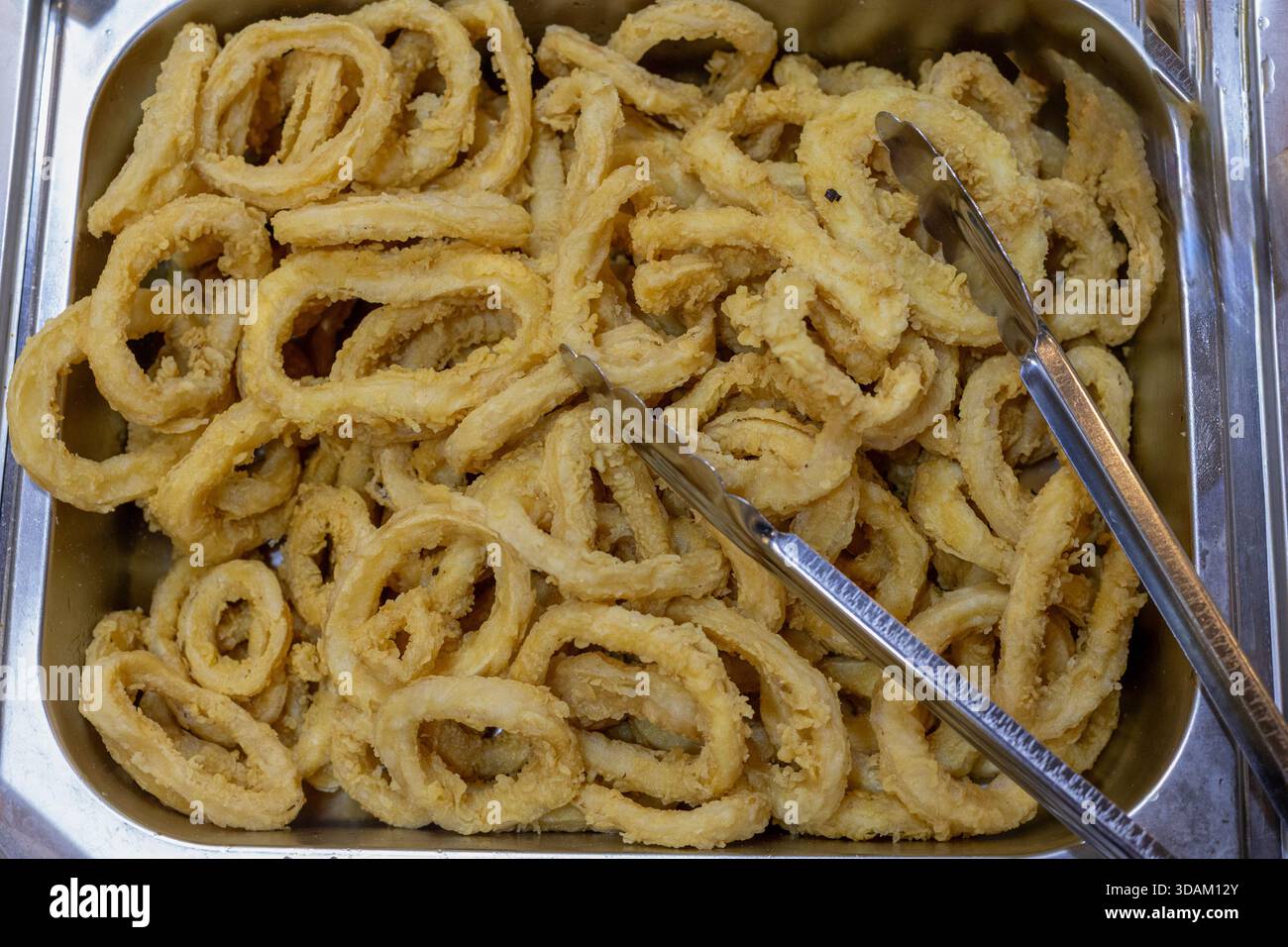 Eine großzügige Portion frittierter Calamari-Ringe, die mit einem leichten Teig überzogen und zu einem perfekten goldgelben Crisp gekocht sind, werden in einem Edelstahl-Tra präsentiert Stockfoto