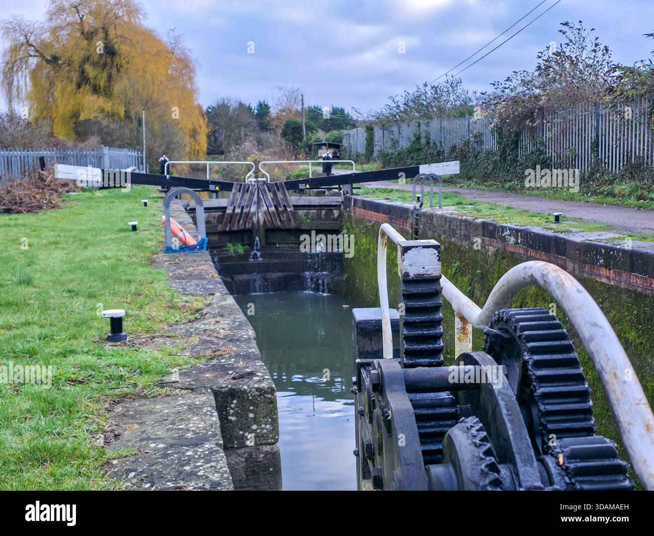 Nahaufnahme der historischen Kanalschleuse mit Zahnrädern, Balancierbalken und offenen Schleusentoren auf dem restaurierten Stroudwater Canal im Winter, Stroud, Cotswolds, Stockfoto